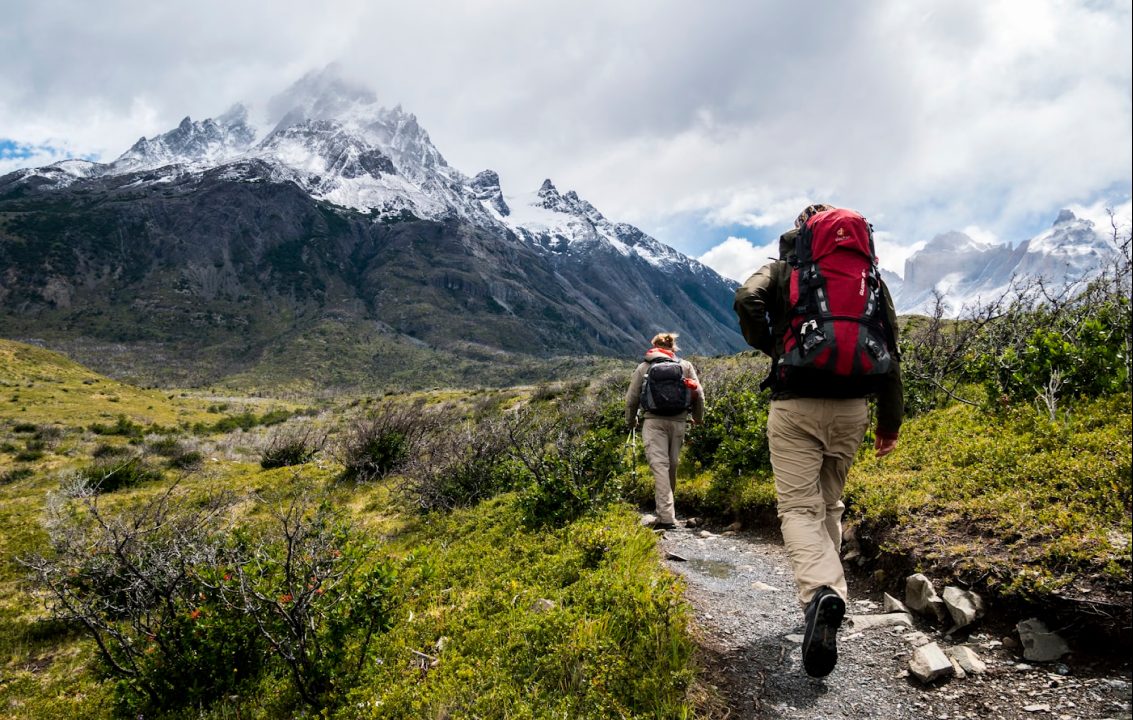 Two trekkers with backpacks on a mountain trail